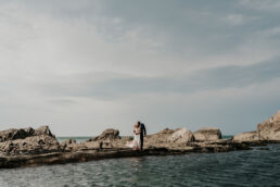bride and groom kissing on the edge of the tidal pool